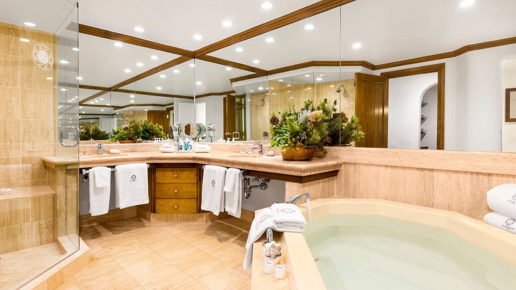 Spacious hotel bathroom with a large spa tub, mirrored walls, marble surfaces, and luxury amenities